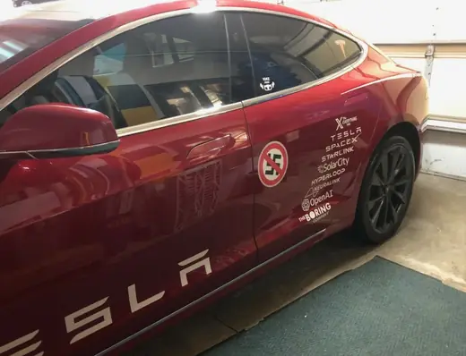 Red Tesla with spaced individual letters along the rocker panel